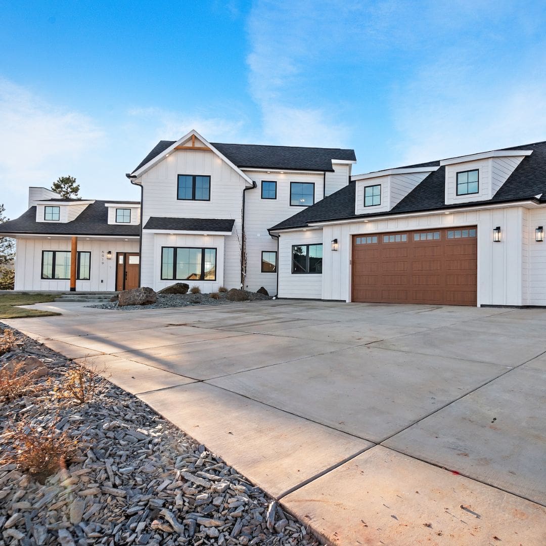 Custom home with white siding, garage and paved driveway