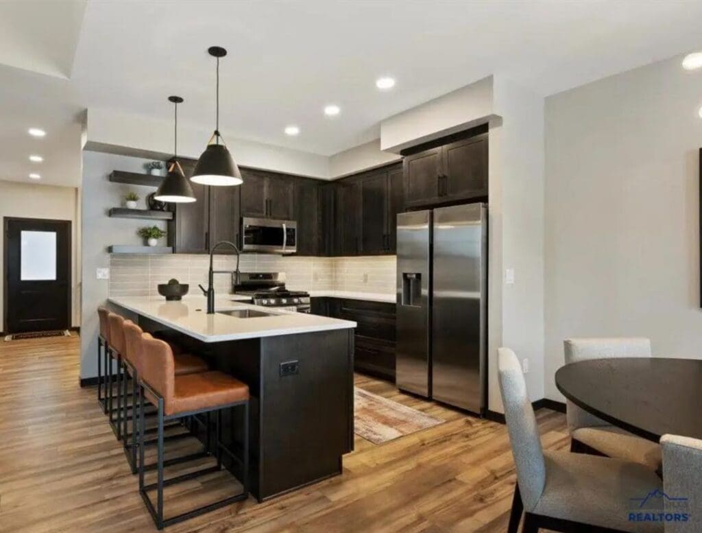 Kitchen with stainless steel appliances, seating next to the island and a dining room table with chairs around it