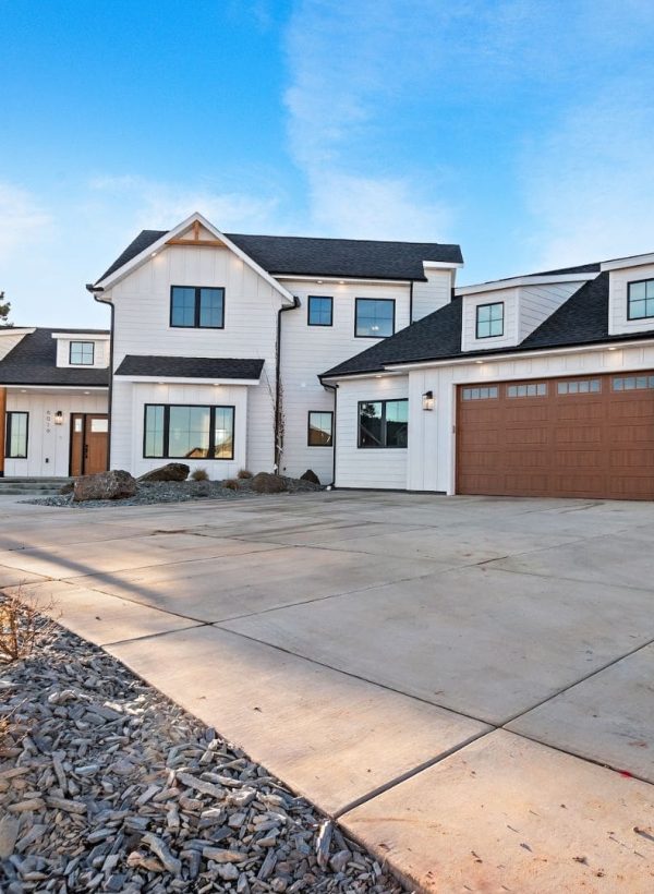 Custom home with white siding, garage and paved driveway
